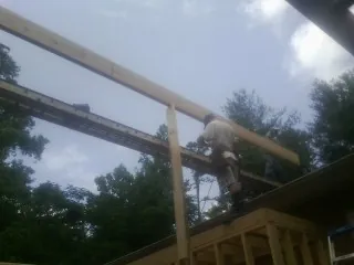 Carpenter setting a ridge beam over a new addition frame — Ice Dam Removal by Roofing Brothers in Oklahoma City