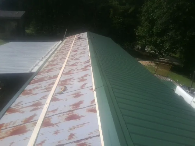Old rusted panels beside newly installed green metal roofing — Wind Damage Roof Repair by Roofing Brothers in Oklahoma City