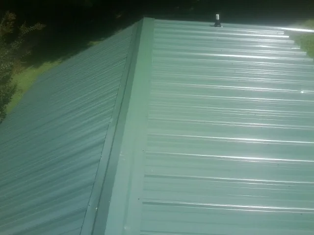 New green metal panels meeting at the ridge of a roof — Flat Roof Repair work by our crew in Oklahoma City