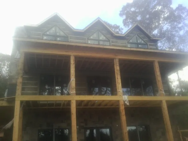 Dormers and porch framing on a large log home under construction — Roof Coating work by our crew in Oklahoma City