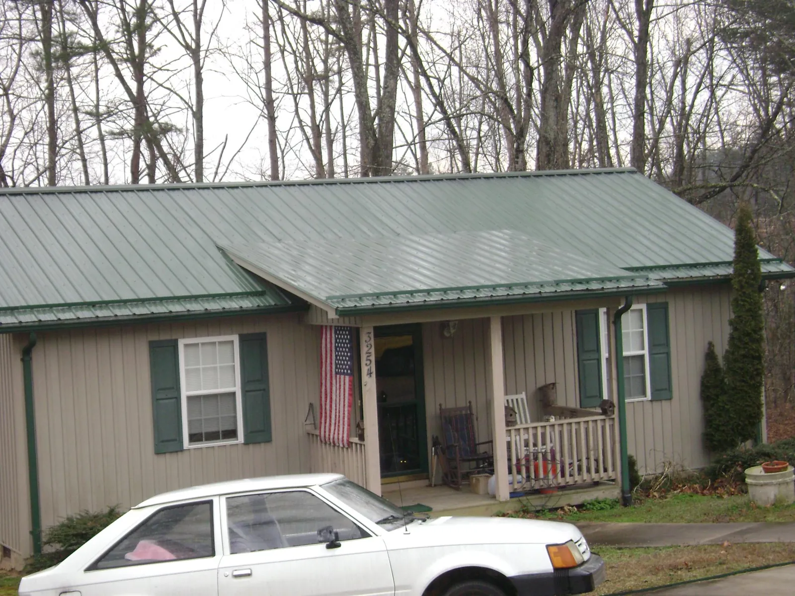Green metal roof and front porch on a tan sided cottage in Oklahoma City