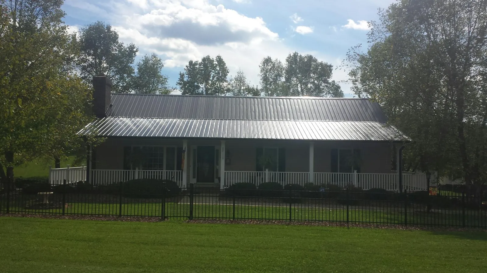 Gray metal roof on a brick ranch with a full width front porch — Gutter Guard Installation work by our crew in Oklahoma City