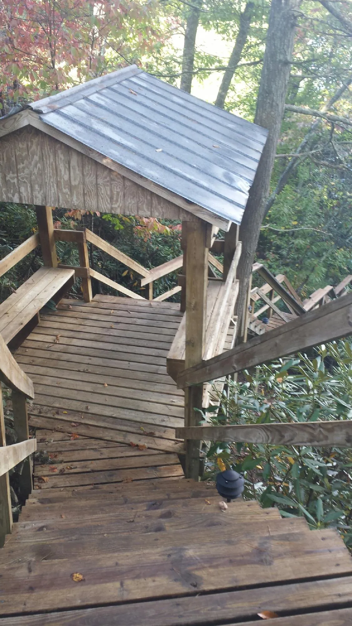 Metal roofed shelter over wooden steps on a wooded walkway — Skylight Repair & Installation work by our crew in Oklahoma City