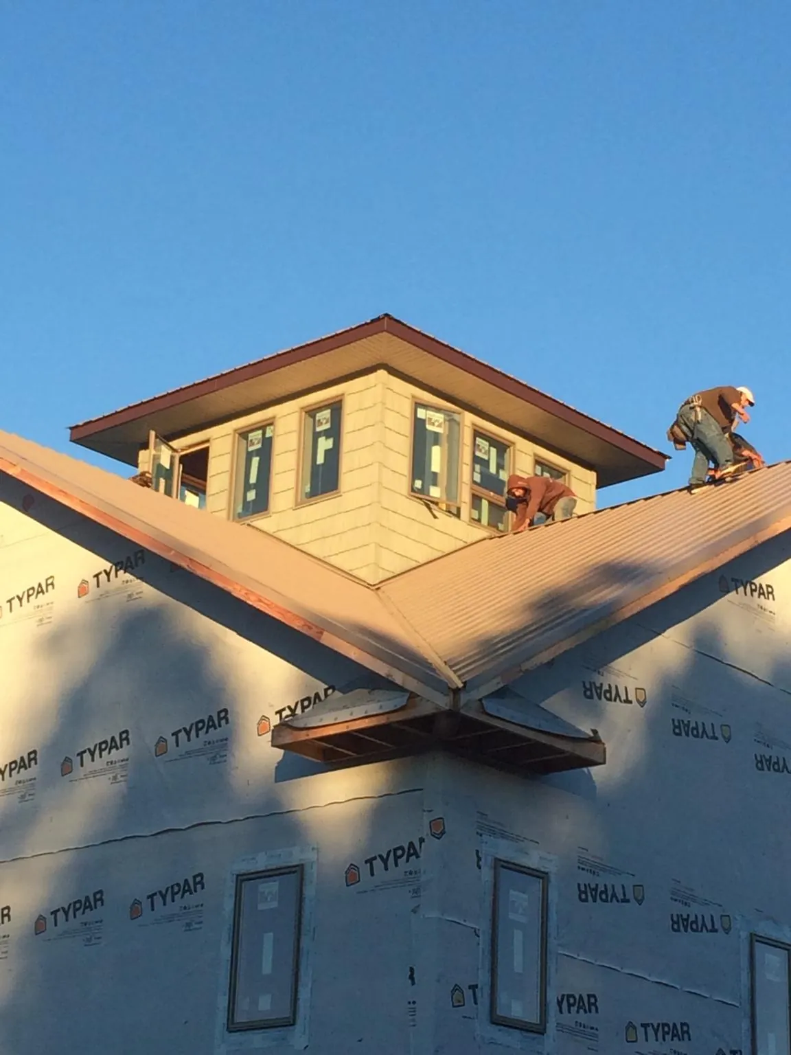 Roofers working around a rooftop cupola on a new metal roof at sunset — Roof Waterproofing in Oklahoma City by Roofing Brothers